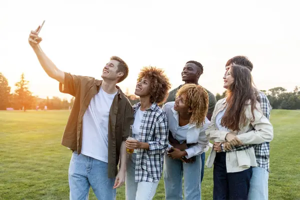 group of multiracial young people take selfies on smartphone and take pictures in the park, interracial students communicate via video communication online outdoors