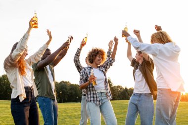 Partide bira şişeleriyle dans eden, dışarıda eğlenen, şarkı söyleyen ve parka taşınan bir grup insan alkol alan ve dinlenen öğrenciler.
