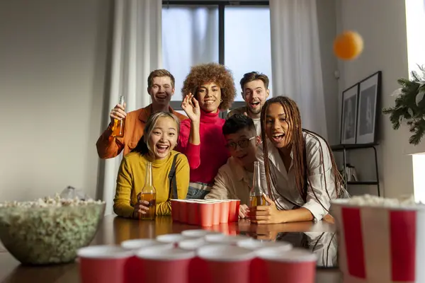 multiracial group of young student friends playing beer pong and drinking beer together at house party, african american girl aiming and throwing ball
