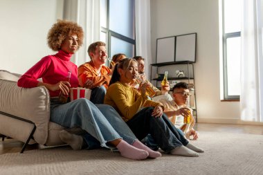 Çok ırklı bir grup genç arkadaş evde kanepede oturup bira içiyor ve televizyon seyrediyor, alkol içiyor, patlamış mısır yiyor ve rahatlıyor.