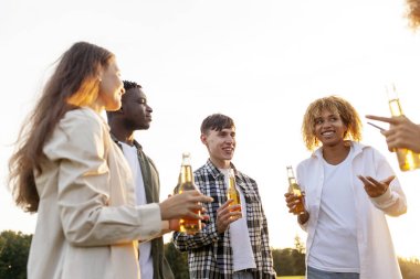 Partide sohbet eden, dışarıda bira içen, Afro-Amerikan kadınlar ve erkekler konuşan, gülen, şişe tutan, eğlenen bir grup insan.