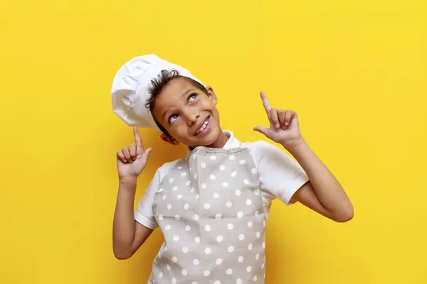 요리사의 유니폼과 모자에 아프리카계 미국인 소년은 노란색 앞치마 포인트에 아이와 스톡 사진