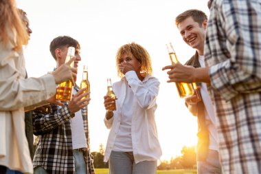 Partide sohbet eden, dışarıda bira içen, Afro-Amerikan kadınlar ve erkekler konuşan, gülen, şişe tutan, eğlenen bir grup insan.