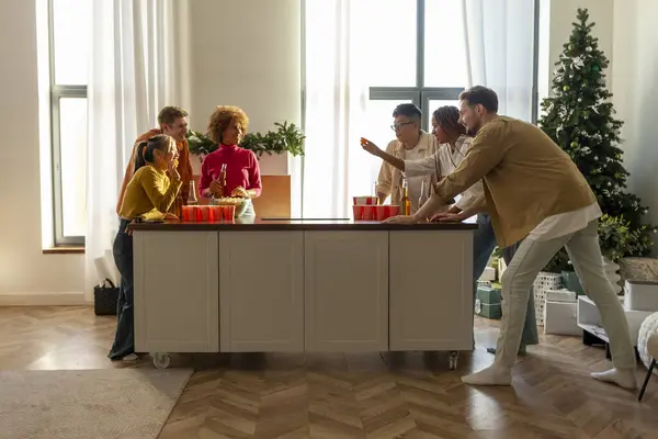 multiracial group of young friends playing beer pong at a New Year\'s party drinking beer and having fun at home, students drinking alcohol and celebrating victory at Christmas