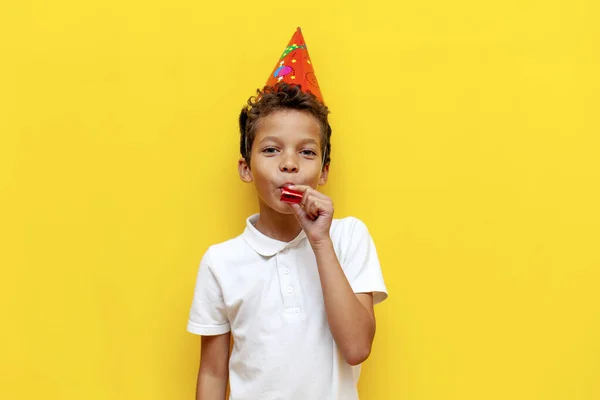 모자에 아프리카계 미국인 소년은 생일을 축하하고 파란색 배경에 나팔을 아이는 스톡 사진
