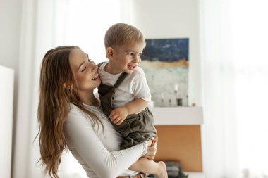 Genç anne, küçük oğlunu kollarına alır ve onu eve kaldırır. 2 yaşındaki çocuk, ebeveyniyle eğlenir ve onunla oynar. Kadın, çocuğu büyütür ve onunla ilgilenir.