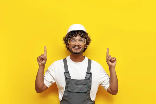Junger Indischer Bauarbeiter Harthut Und Overalls Zeigt Mit Den Händen lizenzfreie Stockbilder