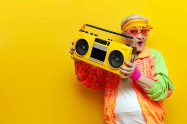 Hippi kıyafetleri içinde, müzik dinleyen, sarı izole edilmiş bir arka planda öpüşen yaşlı ve havalı bir kadın partide dans edip eğleniyor.