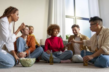 Evde bira ve patlamış mısırla oturan ve arkadaşlarıyla kağıt oynayan farklı etnik kökenli öğrencilerden oluşan çok ırklı bir grup bir partide kumar oynayıp eğleniyorlar.
