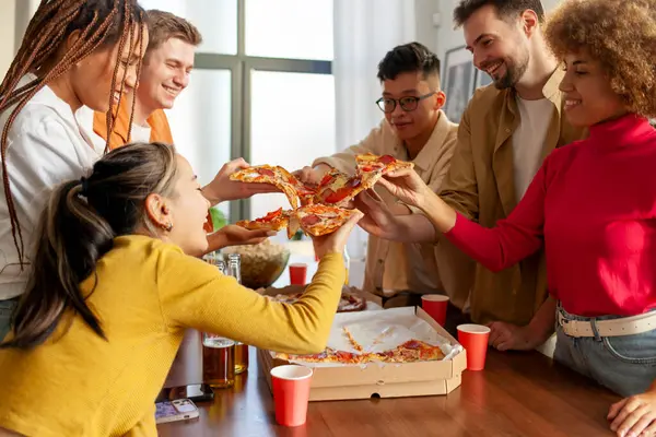 multiracial group of young people at a house party ordered pizza and beer, students of different ethnicities at a house party drink alcohol and eat fast food and have fun