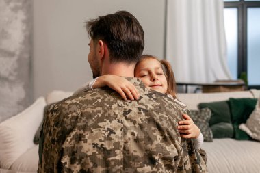 Kamuflaj üniforması içinde Ukrayna ordusunun askeri adamı evine döndü ve kızına sarıldı, asker savaşa gitti ve çocuğuna veda etti, Ukrayna 'daki seferberlik kavramı.