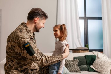 Kamuflaj üniforması içinde Ukrayna ordusunun askeri adamı evine döndü ve kızına sarıldı, asker savaşa gitti ve çocuğuna veda etti, Ukrayna 'daki seferberlik kavramı.