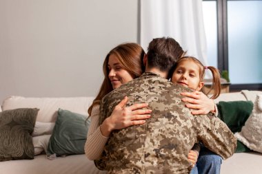 Kamuflaj üniforması içinde Ukrayna ordusunun askeri adamı evine döndü ve ailesine sarıldı, asker savaşa gitti ve Ukrayna 'daki seferberlik kavramı olan kızına ve karısına veda etti.