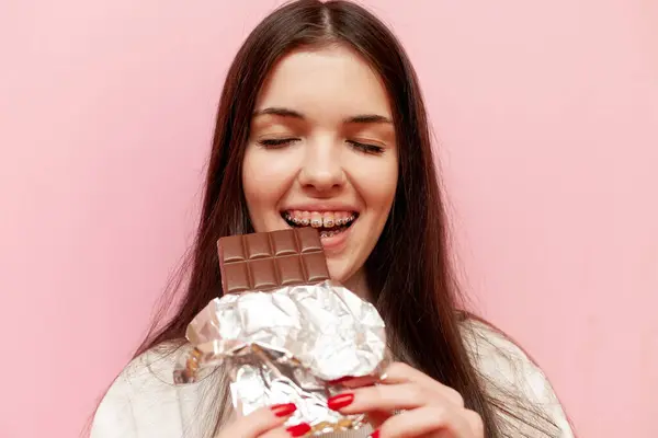 Cheerful Woman Braces Eats Chocolate Smiles Pink Isolated Background Young Stock Photo