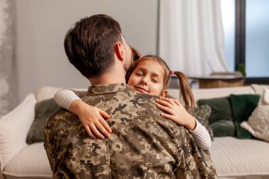 Kamuflaj üniforması içinde Ukrayna ordusunun askeri adamı evine döndü ve kızına sarıldı, asker savaşa gitti ve çocuğuna veda etti, Ukrayna 'daki seferberlik kavramı.