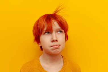 Yorgun kızıl saçlı genç çocuk üzgün ve sarı izole edilmiş arka planda saçlarına üflüyor, turuncu saçlı mutsuz çocuk sıkılmış ve hayal kırıklığına uğramış.