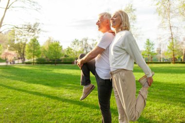 Yaşlı bir çift yaşlı erkek ve kadın parkta egzersiz yapıyor ve antrenman yapıyor, kır saçlı büyükanne ve büyükbaba spor yapıyor ve doğada aktif bir yaşam sürüyor.
