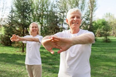 Yaşlı bir çift yaşlı erkek ve kadın parkta egzersiz yapıyor ve antrenman yapıyor, kır saçlı büyükanne ve büyükbaba spor yapıyor ve doğada aktif bir yaşam sürüyor.