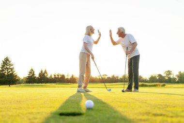 Başarılı bir atıştan sonra spor giyim sektöründe yaşlı bir çift golf sahasında selamlaşır. Erkek ve kadın birlikte oynuyor ve başarıyorlar. Arka planda güneşli gün 