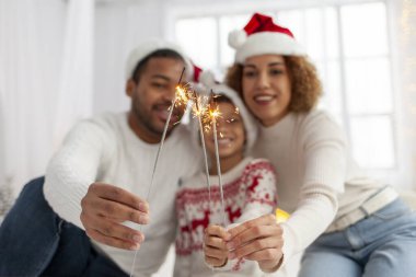 Noel Baba şapkalı Afro-Amerikan ailesi yılbaşını birlikte kutluyor ve Noel ağacının yanında evde maytap tutuyor, anne baba ve küçük oğlu Noel 'de eğleniyor.