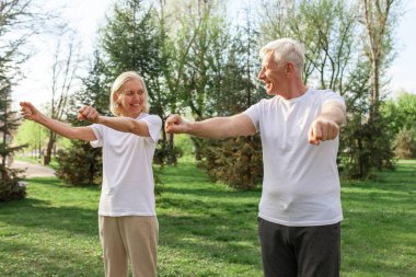 Yaşlı bir çift yaşlı erkek ve kadın parkta egzersiz yapıyor ve antrenman yapıyor, kır saçlı büyükanne ve büyükbaba spor yapıyor ve doğada aktif bir yaşam sürüyor.