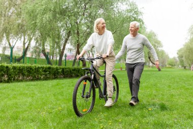 Dedem büyükanneme parkta bisiklet sürmeyi öğretiyor ve yaşlılara yardım ediyor.