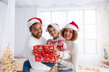 Noel Baba şapkalı Afro-Amerikan ailesi Noel 'de evde sarılıyor ve oğluna hediye veriyor. Yeni yılı anne ve babasıyla kutluyor ve evi dekore ediyor. Ebeveynler çocuklara hediye paketi veriyor.