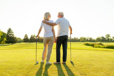 Golf sahasında golf oynayan yaşlı bir çift yaşlı bir adam, kadınlara golf sopası ve salıncak topunu nasıl tutacağını öğreten yaşlı bir öğretmen, büyükannenin dışarıda oynamasına yardım eden büyükbaba.