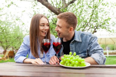 Birbirine aşık genç bir çift parkta kırmızı şarapla bardakları tokuşturuyor, güzel bir kız ve erkek randevuda şarap içiyor ve bahçede alkollü kokteyller içiyor.