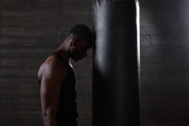 Yorgun, üzgün, kırmızı eldivenli Amerikalı boksör elleri kum torbasının yanında durur ve düşünür ki, şaşkın sporcu kaybeder ve depresyona girer.