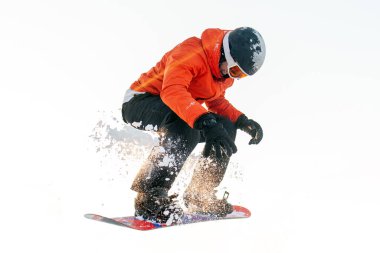 Kayak turuncu elbiseli genç adam beyaz izole edilmiş arka planda snowboard 'a atlıyor, ceketli, kasklı ve gözlüklü adam havada hile yapıyor ve snowboard ile uçuyor.