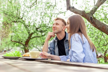 Kot elbiseli genç bir çift, tahta masanın bahçesinde oturuyor ve yazın fotokopi odasına bakıyor. Erkek ve kız, parkta buluşup düşünüyor ve hayal görüyorlar.
