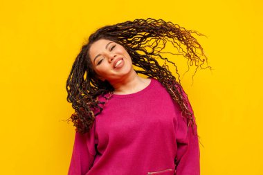 Sarıya boyanmış arka planda saçlarını sallayan, sırıtan, iri yarı, iri yarı, dans eden Afrikalı Amerikalı bir kadın.