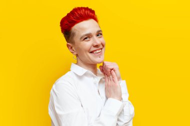 Genç, kısa saçlı, kızıl saçlı, minnettar kız duygulanmış ve utangaçtır. Sarı, izole bir arka planda, piercing gülüşlü, mütevazı bir hipster kadın ve teşekkürler.