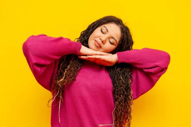 Yorgun, tombul, saçları örgülü, sarı arka planda uyuyan ve dinlenen Afro-Amerikan kadını artı uzun boylu, uzun saçlı, uyku jesti yapan ve rüya gören bir kız.