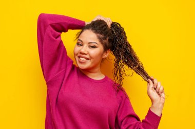 Saçları sarı izole edilmiş, sırıtan, saçları olan, saçları sarı saçlı, at kuyruklu iri yarı, uzun saçlı, kameraya bakan Afrikalı Amerikalı bir kadın.