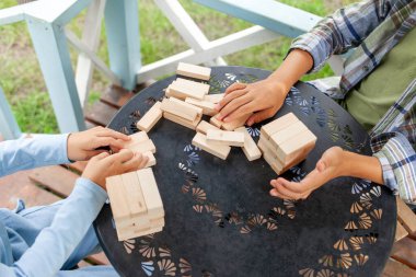 Tahta eğitim oyunu oynayan ve ahşap bloklardan kule inşa eden çocuklar, erkek ve kız kardeşler yarışıyor.