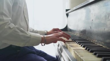 Beyaz gömlekli genç adam piyanoda klasik müzik çalıyor, müzisyen müzik aletinde melodi çalıyor, yakın plan.