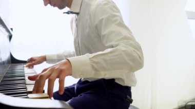 Beyaz gömlekli genç adam piyanoda klasik müzik çalıyor, müzisyen müzik aletinde melodi çalıyor, yakın plan.