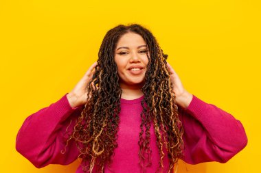 Saçları sarı izole edilmiş, sırıtan, saçları olan, saçları sarı saçlı, at kuyruklu iri yarı, uzun saçlı, kameraya bakan Afrikalı Amerikalı bir kadın.