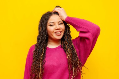 Sarı izole edilmiş arka planda gülümseyen iri yarı, at kuyruklu ve kameraya bakan şişman Afrikalı Amerikalı kadın.