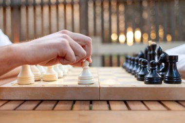 Erkek eli ilk hamleyi tahta masada piyon içinde yapar, adam yakın plan masa oyunu oynar.