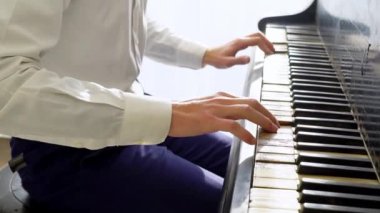 Beyaz gömlekli genç adam piyanoda klasik müzik çalıyor, müzisyen müzik aletinde melodi çalıyor, yakın plan.