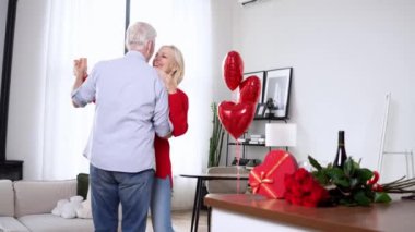 Sevgili yaşlılar Sevgililer Günü 'nü evde kutluyor ve vals yapıyor. Yaşlı adam karısını çiçekler ve şarapla tebrik ediyor. Romantik randevudaki emekliler.