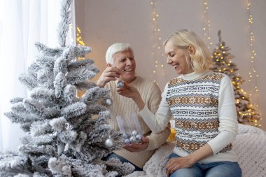 Bir çift yaşlı süveter içinde yeni yılı evde kutluyor ve ağacı süslüyorlar. Gri saçlı yaşlı büyükbaba ve karısı Noel için evi hazırlıyorlar.