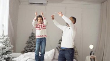 Yeni yılda oğluyla birlikte Afrika kökenli Amerikalı bir adam Noel 'i ağaç kenarında kutluyor, baba ve çocuk birlikte seviniyor ve yeni yıl gelenekleriyle eğleniyor.