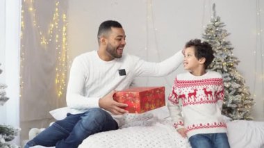 Afrika kökenli Amerikalı bir çocuk yeni yılda evde babasına hediye veriyor. Bir adam hediye kutusunu açıyor ve oğluna sarılıyor. Yeni yıl kıyafetleri içinde bir aile kutluyor.