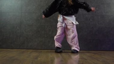 Dans salonunda ayaklarıyla hip hop yapan eşofmanlı genç bir kız. Dans eden koreografların ayaklarının yakın çekimi.