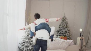 Afrika kökenli Amerikalı bir baba Noel kıyafetleri içinde oğluyla eğleniyor, ebeveynlerinin sırtına oturmuş ve uçuyormuş gibi yapıyor, Noel 'i evde kutluyor ve dans ediyor.