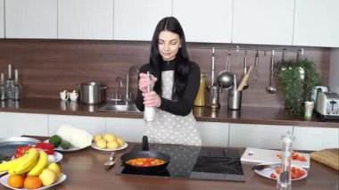 Genç kadın mutfakta çırpılmış yumurta hazırlıyor, kız omlete tuz ve baharat ekliyor.